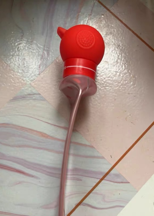 Red silicone tool with a long flexible hose on a tiled floor
