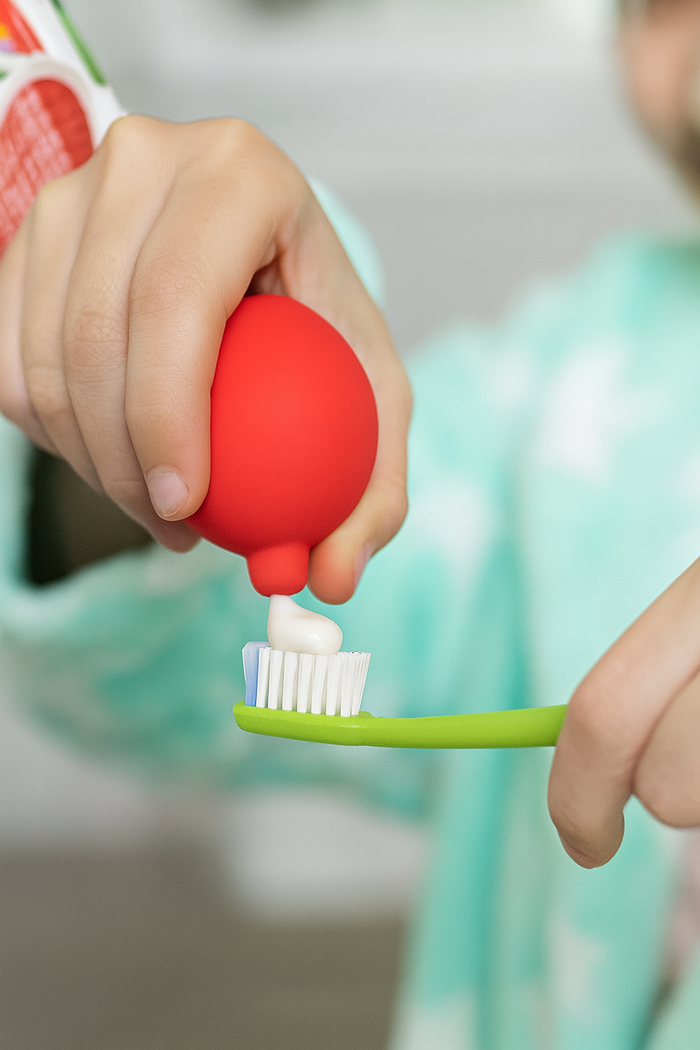 a kid using SqueezeBuddies Fire buddie toothpaste squeezer