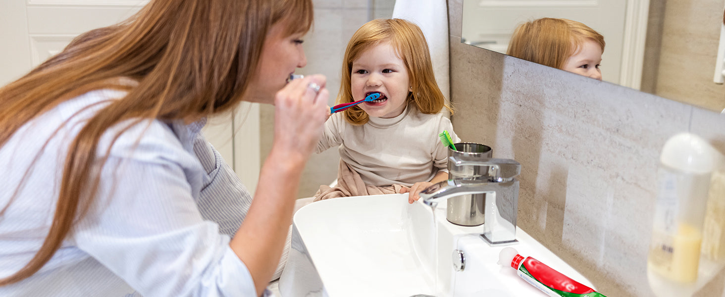 Toddler brushing teeth at sink using a mess-free toothpaste dispenser 